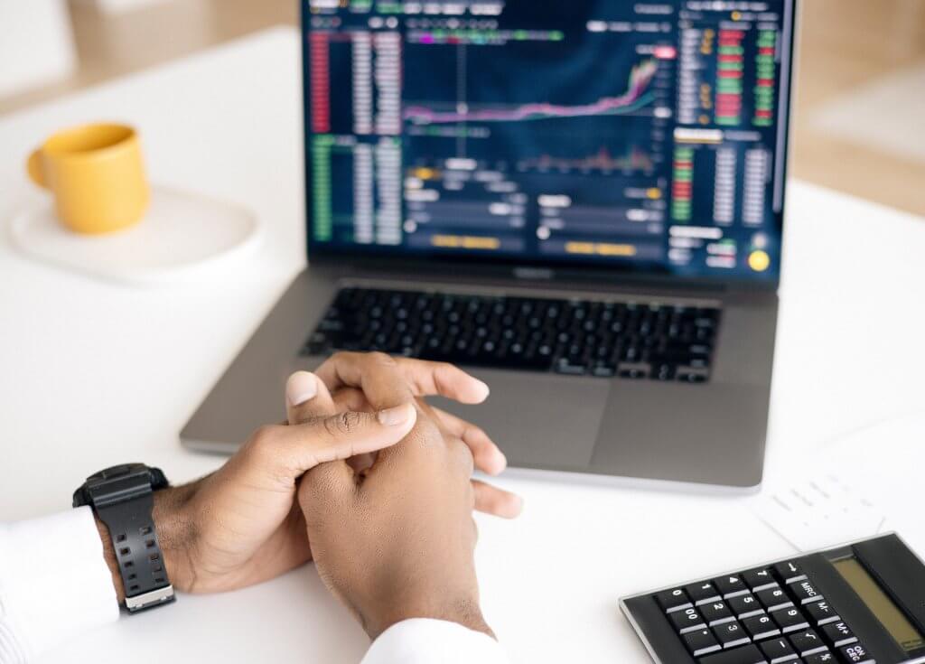 Man sitting down viewing stock market on laptop
